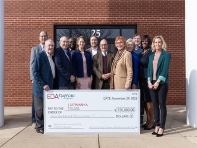 Stafford EDA members, Stafford Board of Supervisors members and Germanna Leadership members standing in front of new education site location with a large check